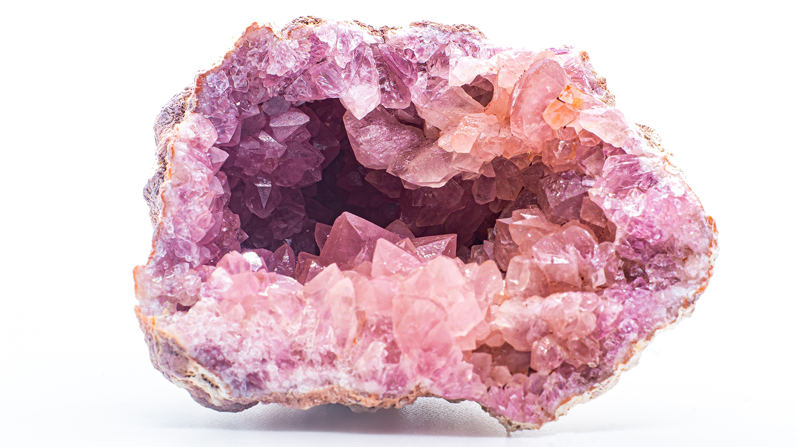 Macro focused vibrant pink amethyst quartz geode crystal, rose hematite amethyst points isolated on a white background surface